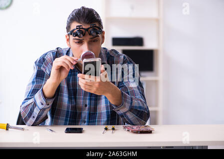 Le jeune beau téléphone mobile réparation technicien Banque D'Images