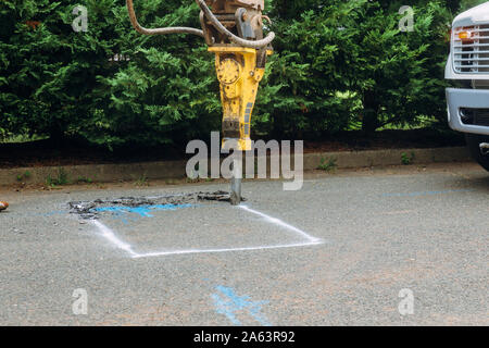 Travailleur de la construction réparation route avec digger exploitation Jackhammer Banque D'Images