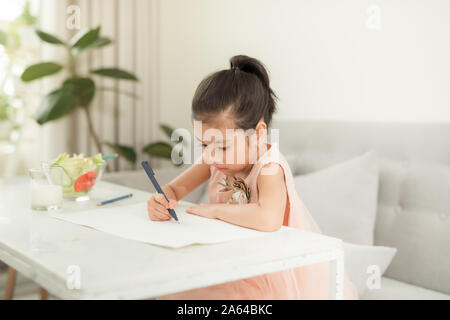 Petite fille dessin photo à table avec les outils de peinture à l'intérieur Banque D'Images