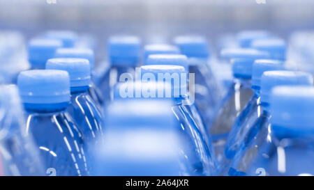 Arrière-plan flou artistique, de l'eau potable dans des bouteilles en plastique, Capsules de bouteille bleu. Fond bleu fond d'écran boissons close-up Banque D'Images