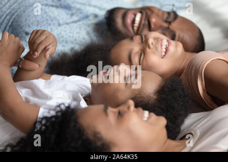 Close up of happy black family vous détendre sur le même lit