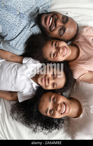 Top View portrait of smiling black family lying on bed Banque D'Images