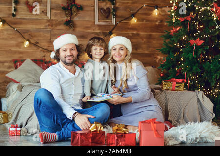 Family smiling dans la maison avec un arbre de Noël Banque D'Images