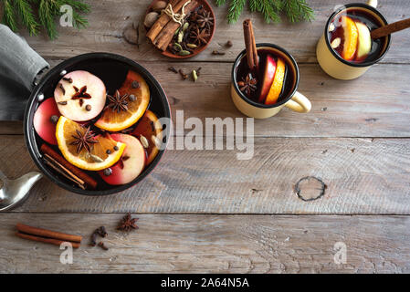 Vin chaud pour Noël et vacances d'hiver. Boire de vin chaud avec des fruits et d'épices en cocotte et tasses sur fond de bois, vue du dessus, copiez Banque D'Images