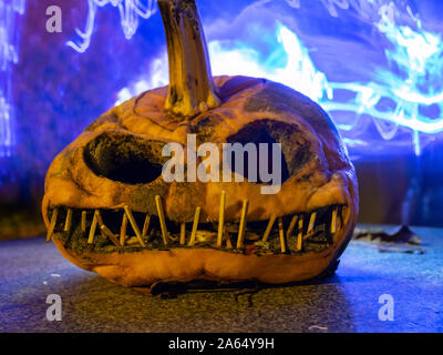 Citrouille sculptée terrible et dessins de lumière colorée à l'arrière-plan, adapté pour l'Halloween Banque D'Images