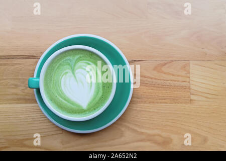 Une tasse de thé matcha latte avec le dessin sur la table en bois, Banque D'Images