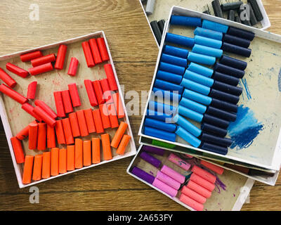 Boîtes de pastels à l'huile, bleu, rose sur un plancher en bois Banque D'Images