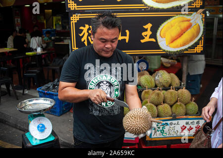 24.02.2019, Singapour, République de Singapour, en Asie - Un vendeur coupe ouvrir un durian frais avec un couteau sur un marché de rue dans le quartier chinois. Banque D'Images