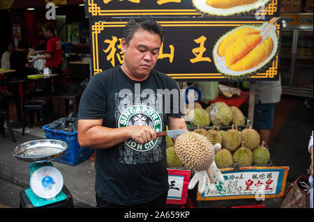 24.02.2019, Singapour, République de Singapour, en Asie - Un vendeur coupe ouvrir un durian frais avec un couteau sur un marché de rue dans le quartier chinois. Banque D'Images