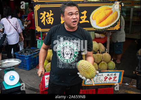 24.02.2019, Singapour, République de Singapour, en Asie - Un fournisseur est titulaire d'un durian frais et un couteau à la main au cours d'un marché de rue dans le quartier chinois. Banque D'Images