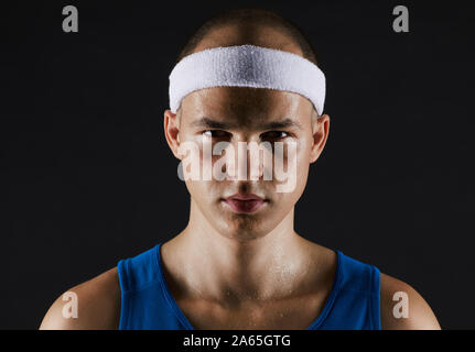Portrait de jeune homme séduisant dans les vêtements de sport à la caméra à isolé sur fond noir Banque D'Images