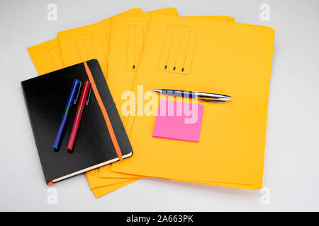 Fournitures de bureau moderne composé d'un stylo et bloc-notes jaune fuchsia sur sous-dossiers Banque D'Images