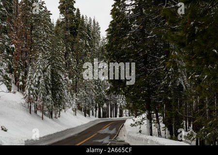 L'autoroute 120 sur la route vers le Yosemite, California, USA, sur une journée d'hivers la neige sur le côté de la route comme un signe de la conduite dangereuse co Banque D'Images