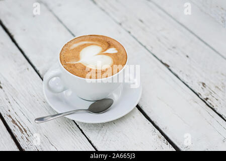 Gros blanc délicieuse tasse de café avec un cœur en forme sur l'art de la table en bois blanc, avec l'exemplaire de l'espace. Vue d'en haut. Banque D'Images