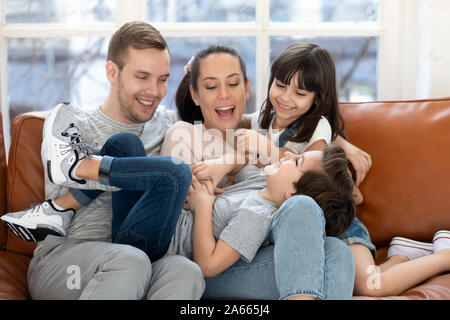 Les parents heureux et souriant fille chatouillant son frère rire. Banque D'Images
