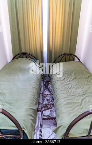 Simple auberge Chambre lits jumeaux avec draps et rideaux de couleur Orange Box modeste Banque D'Images