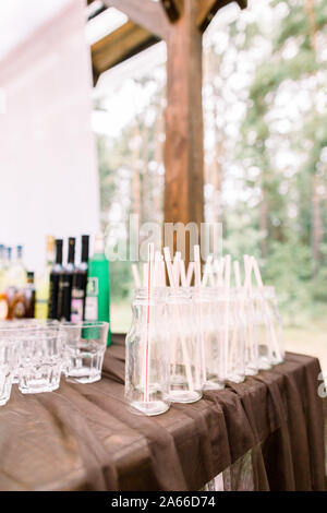 Table avec des verres et bouteilles d'alcool sur l'arrière-plan. Célébration le brunissage à réception de mariage concept. Mariage dans un style rustique en plein air Banque D'Images