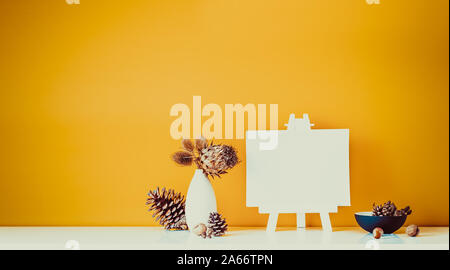 Composition de fleurs séchées, les épines à la lumière vase, pommes de pin et toile vierge sur un mur de couleur ocre sur l'arrière-plan. Accueil simple et naturel interi Banque D'Images