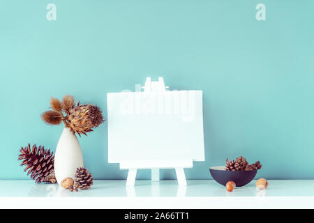 Composition de fleurs séchées et les épines en vase lumineux, pommes de pin et vide toile vierge sur un mur turquoise sur fond. Eco, foyer naturel dans Banque D'Images