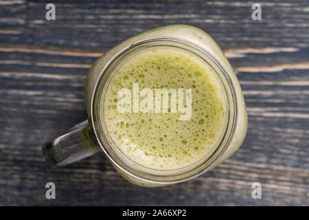 Smoothie vert frais de l'avocat, kiwi, banane, miel, l'aneth et le persil dans la tasse en verre sur fond de bois, Close up, vue du dessus. Concept de manger sain Banque D'Images