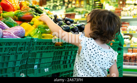 Shopping enfant poivrons en supermarché. Concept pour l'achat de fruits et légumes dans les hypermarchés. Petite fille tenir panier. Banque D'Images