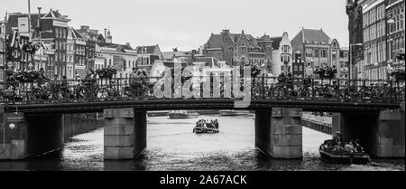 Une photo en noir et blanc d'un pont plein de vélos sur un canal à Amsterdam. Banque D'Images