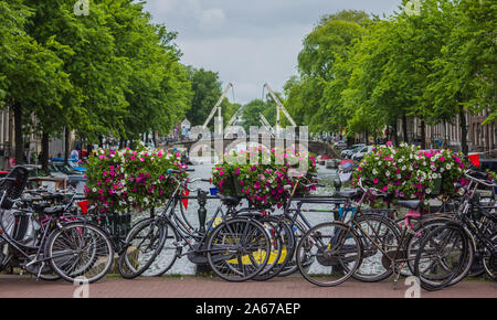 Une photo d'un pont plein de vélos et de fleurs sur un canal à Amsterdam. Banque D'Images