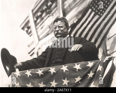 Theodore Roosevelt sur une plate-forme, recouvert du drapeau, avec le chapeau à la main lors de sa tournée à travers le New Jersey avant le congrès du Parti progressiste, Septembre 1912 Banque D'Images