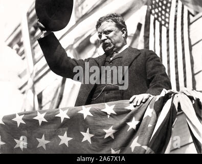 Theodore Roosevelt sur une plate-forme, recouvert du drapeau, agitant son chapeau lors de sa tournée à travers le New Jersey avant le congrès du Parti progressiste, Septembre 1912 Banque D'Images