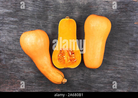 Pumpkin sur une table en bois noir. En forme de poire douce trois orange citrouille. La moitié pumpkin cutted sur milieu Banque D'Images