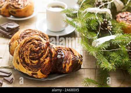 Muffins au chocolat escargot servi avec du café sur l'arrière-plan d'une couronne de branches de sapin et les cônes. Style rustique. Banque D'Images