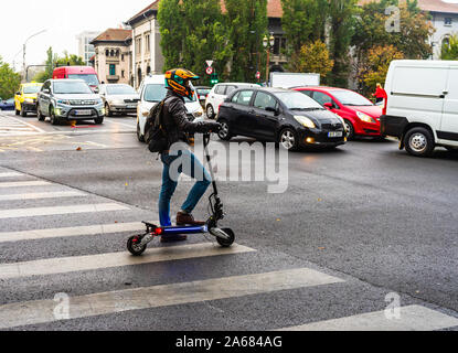 Jeune homme avec casque sur scooter électrique en centre-ville de Bucarest, Roumanie, 2019 Banque D'Images