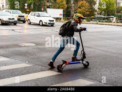 Jeune homme avec casque sur scooter électrique en centre-ville de Bucarest, Roumanie, 2019 Banque D'Images