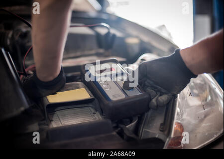 Location de maître mécanicien réparateur automobile contrôle et essai avec l'accumulateur batterie électronique numérique testeur et analyseur en atelier véhicule auto Banque D'Images