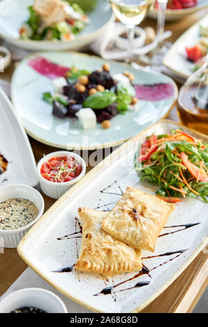 Empanadas frites d'Amérique latine avec une salade de légumes avec la roquette. Variété de plats sur la table. Divers en-cas et antipasti sur la table Banque D'Images