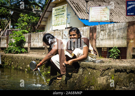 Alleppey - Alappuzha, Inde - 13 novembre 2017 : élèves filles lavant leurs coupes le long de la rivière dans le Kerala backwater canal Banque D'Images