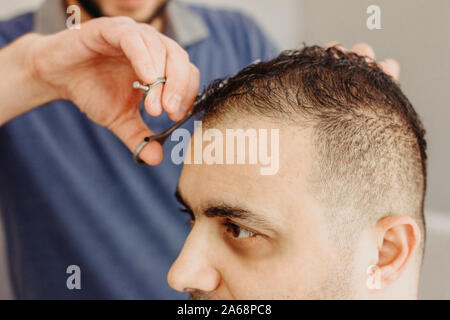 Salon de coiffure faisant coupe élégante avec professional scissers dans barber shop. Couper les cheveux d'un turc Banque D'Images