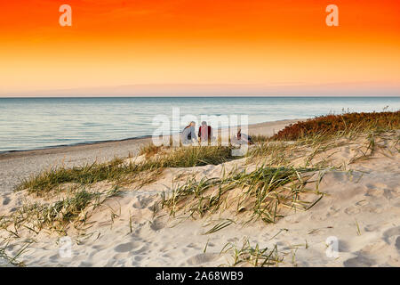 Jeune couple sur une plage au coucher du soleil. Fond romantique. Mer. Banque D'Images