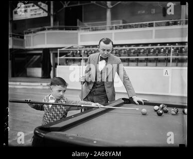 Champion du Monde Washington montres cue bébé jouer avec l'assistant d'ivoires. Atteignant tout juste son sixième anniversaire et à peine capable de voir au-dessus de la table, Andrew M. Dargan, fils d'un Washington [...] salle de billard propriétaire, est étonnant de billard pocket expert avec sa maîtrise des coups complexes sur la toile verte. Il est indiqué dans cette photographie de prendre quelques conseils d'Irwin Rudolph, champion du monde de billard de poche qui est à Washington pour une exposition Banque D'Images