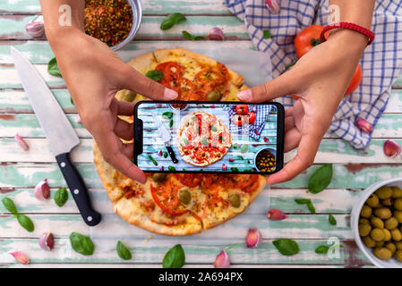 Femme à prendre des photos d'une pizza au feu de bois rustique, vu de dessus, sur les conseils de turquoise Banque D'Images