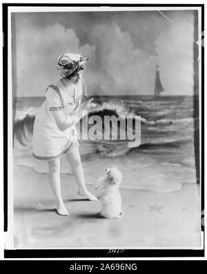 Jeune femme en maillot de bain avec petit chien en face de fond de studio beach Banque D'Images