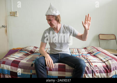 Jeune homme a souligné avec tin foil hat montrant le geste d'arrêt dans la chambre à coucher Banque D'Images