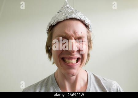 Visage de jeune homme a souligné avec tin foil hat avoir peur à l'intérieur de la chambre Banque D'Images