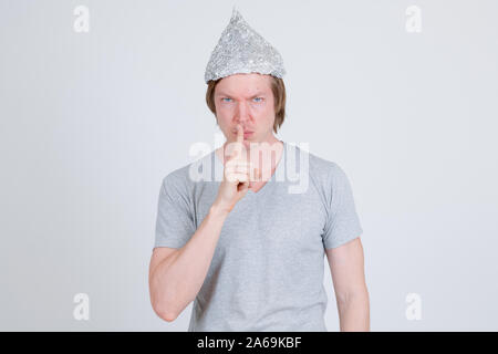 Jeune homme avec du papier d'aluminium hat avec le doigt sur les lèvres Banque D'Images