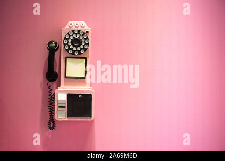 Old vintage téléphone accroché sur un mur rose with copy space Banque D'Images
