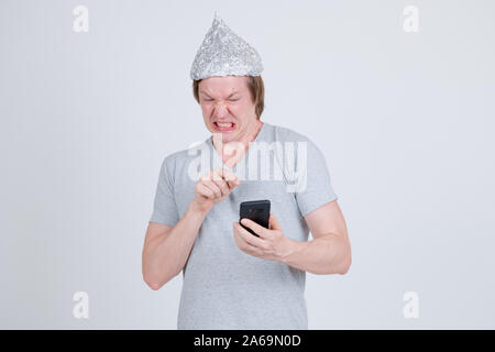 Jeune homme a souligné avec du papier d'aluminium hat en utilisant le téléphone et à la peur Banque D'Images