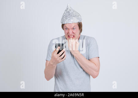 Jeune homme a souligné avec du papier d'aluminium hat en utilisant le téléphone et à la peur Banque D'Images