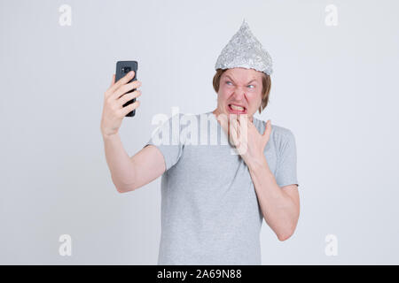 Jeune homme a souligné avec du papier d'aluminium hat en tenant à la peur et selfies Banque D'Images