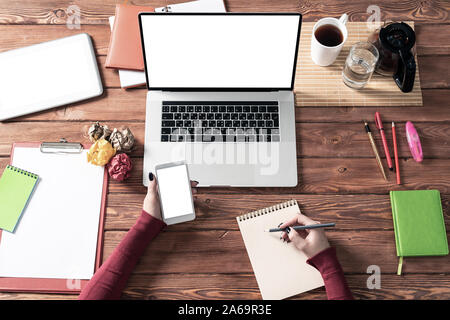 Business Woman using smartphone à bureau. Affaires en ligne app concept. Bureau de travail avec mise à plat des mains des femmes, des ordinateurs portables et des documents. Digita Banque D'Images