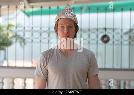 Jeune homme portant une feuille de papier aluminium hat comme théorie du complot extérieur concept Banque D'Images